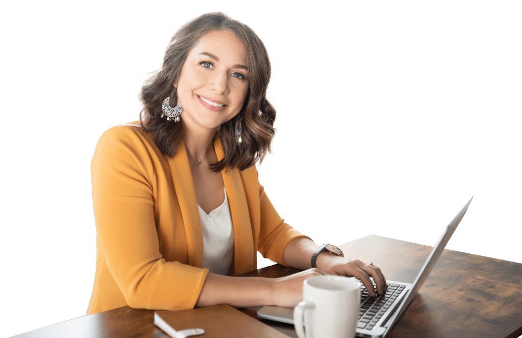 A brown haired woman sits at a desk with a laptop and coffee cup.